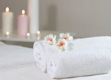 Rolled towels and flowers at Thai Wellness Room Inverness, Scotland, GB with soft candlelight.