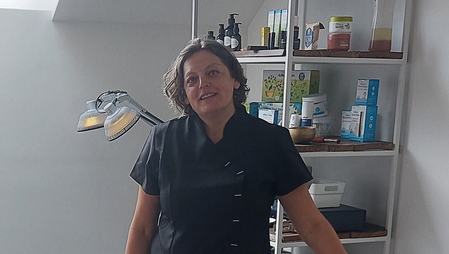 Glunderende schoonheidsspecialiste in Meldert, Hoegaarden, Vlaanderen, BE naast een goed gevulde plank schoonheidsproducten.