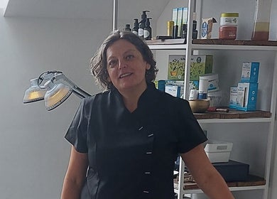 Glunderende schoonheidsspecialiste in Meldert, Hoegaarden, Vlaanderen, BE naast een goed gevulde plank schoonheidsproducten.