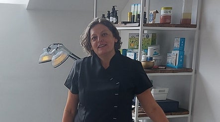 Glunderende schoonheidsspecialiste in Meldert, Hoegaarden, Vlaanderen, BE naast een goed gevulde plank schoonheidsproducten.