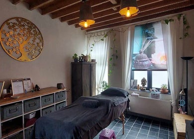 Rustieke wellnessruimte bij Heers in Vlaanderen, BE met massagebed en warme decoraties.