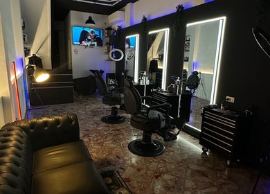 Stylish interior of DEEP HAIR premium cut & shave in Romano Di Lombardia, Lombardia, IT with sleek chairs and mirrors.