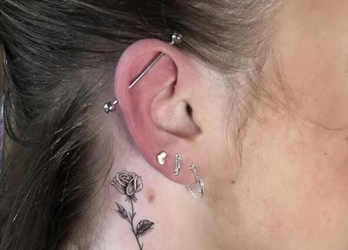 Intricate rose tattoo and multiple piercings at Liverpool Tattoos Orrell Park, Liverpool, England, GB.