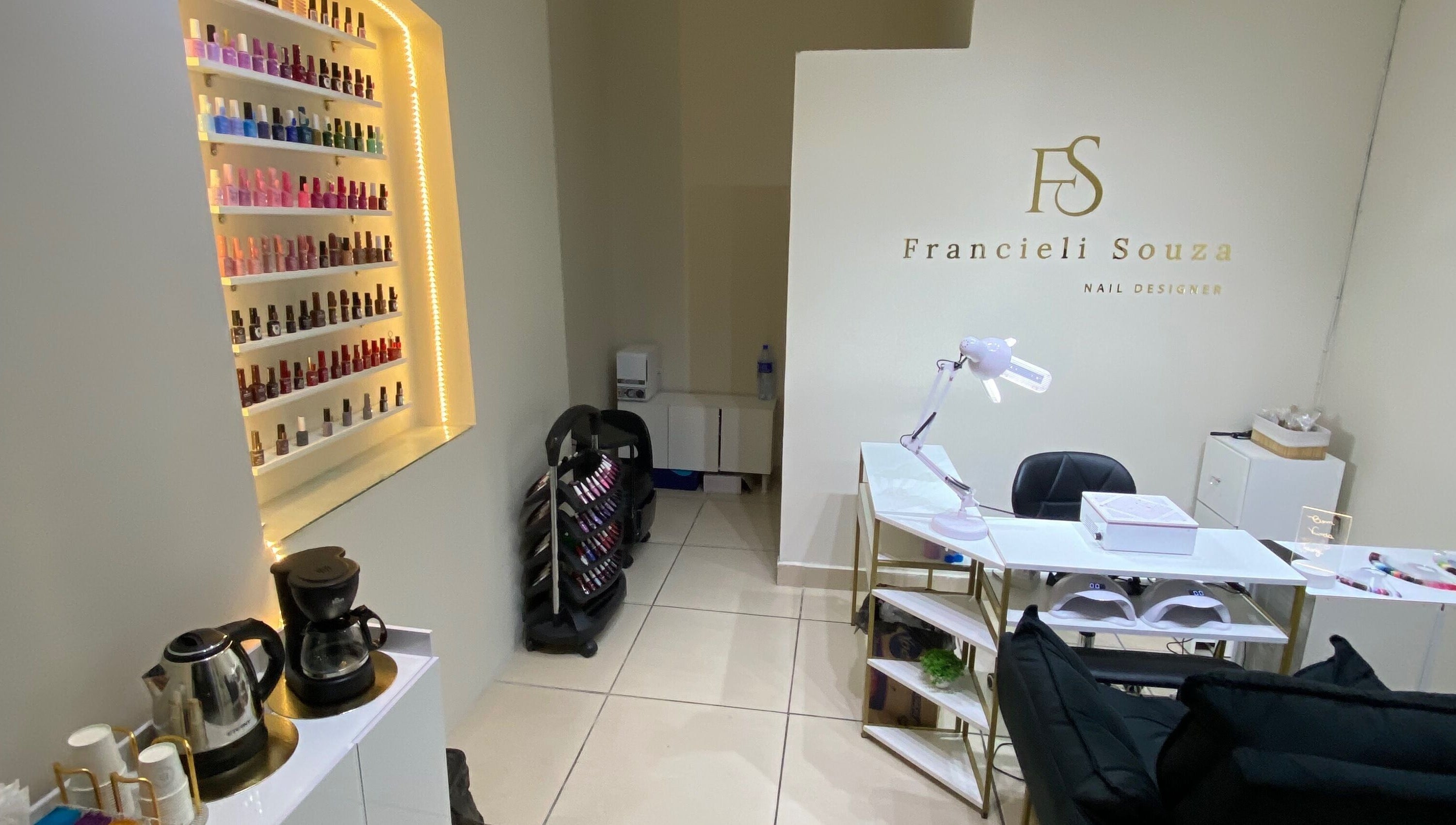 Interior do Fran Souza Nails em São Paulo, BR, exibindo polidores de unhas e estação de trabalho elegante.