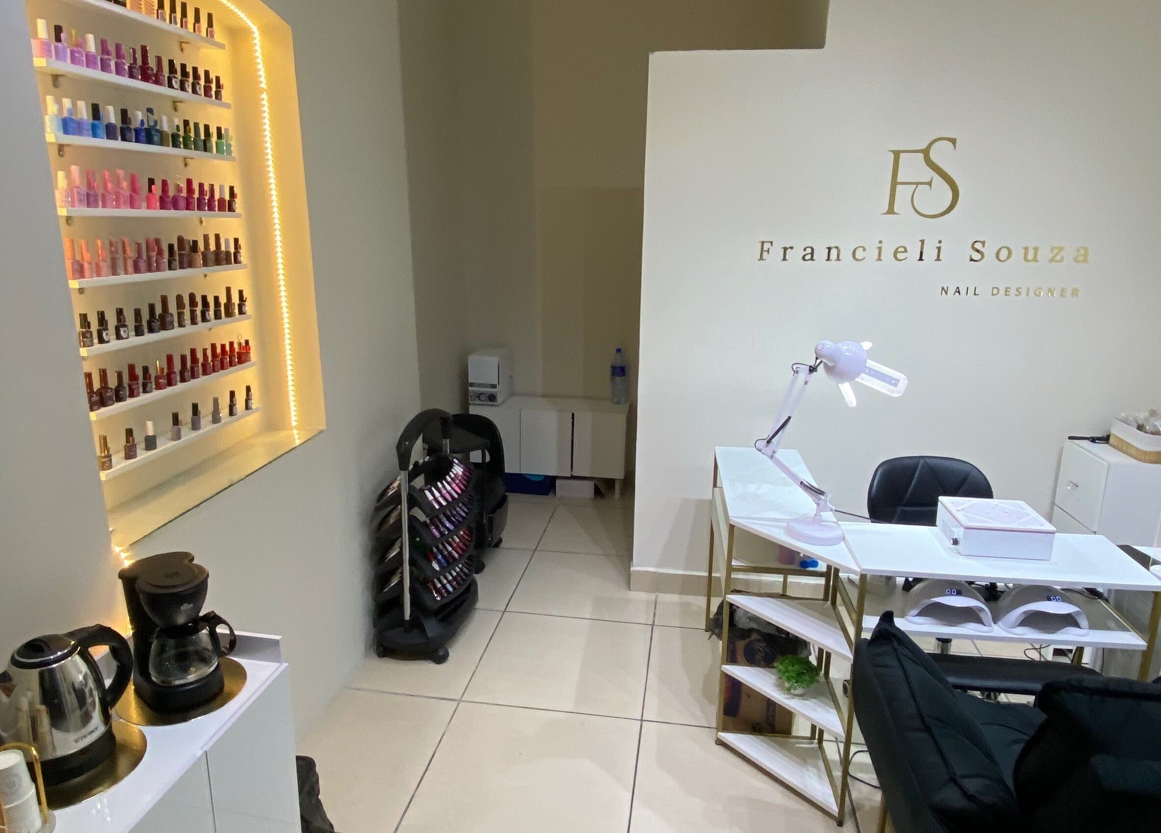 Interior do Fran Souza Nails em São Paulo, BR, exibindo polidores de unhas e estação de trabalho elegante.