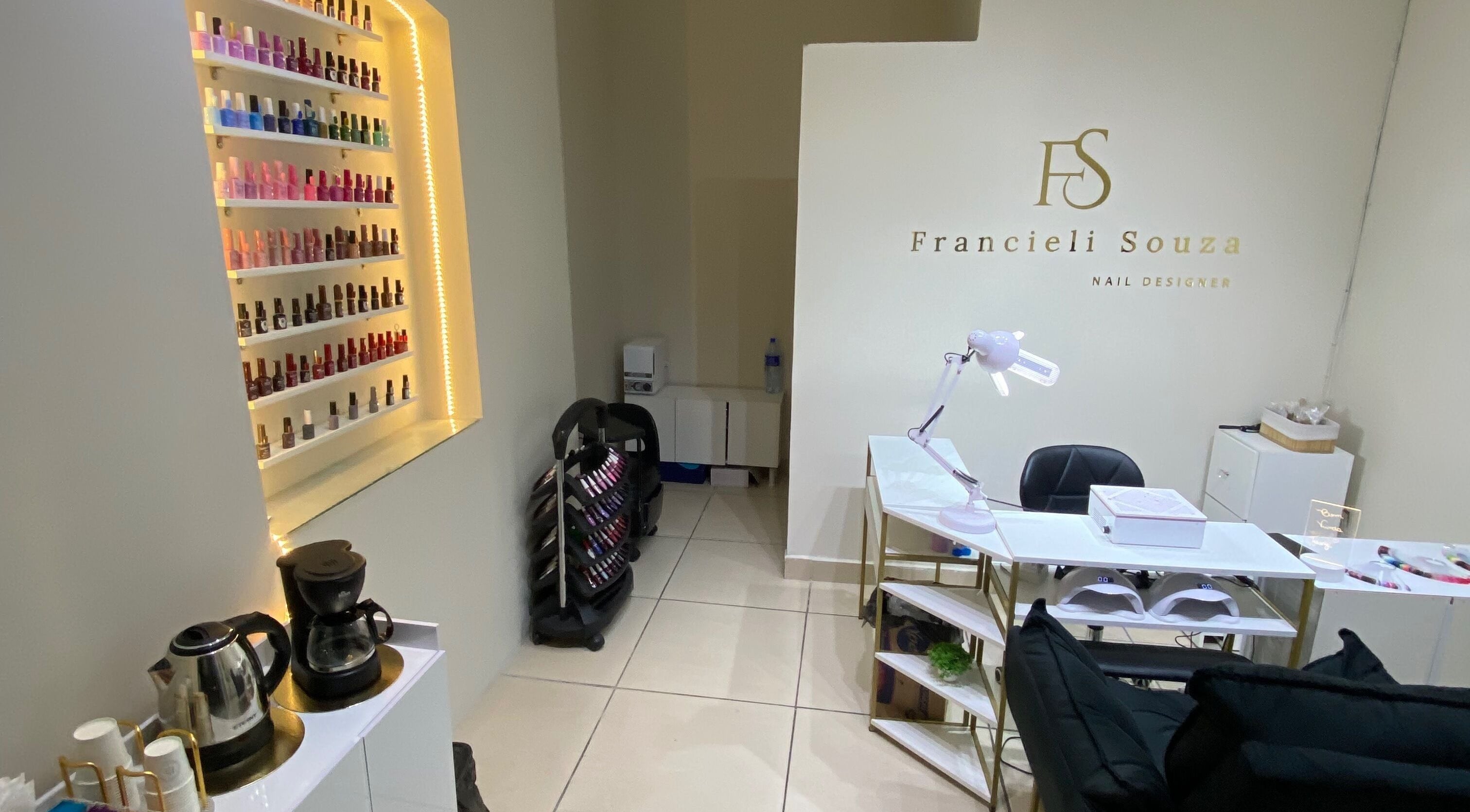 Interior do Fran Souza Nails em São Paulo, BR, exibindo polidores de unhas e estação de trabalho elegante.
