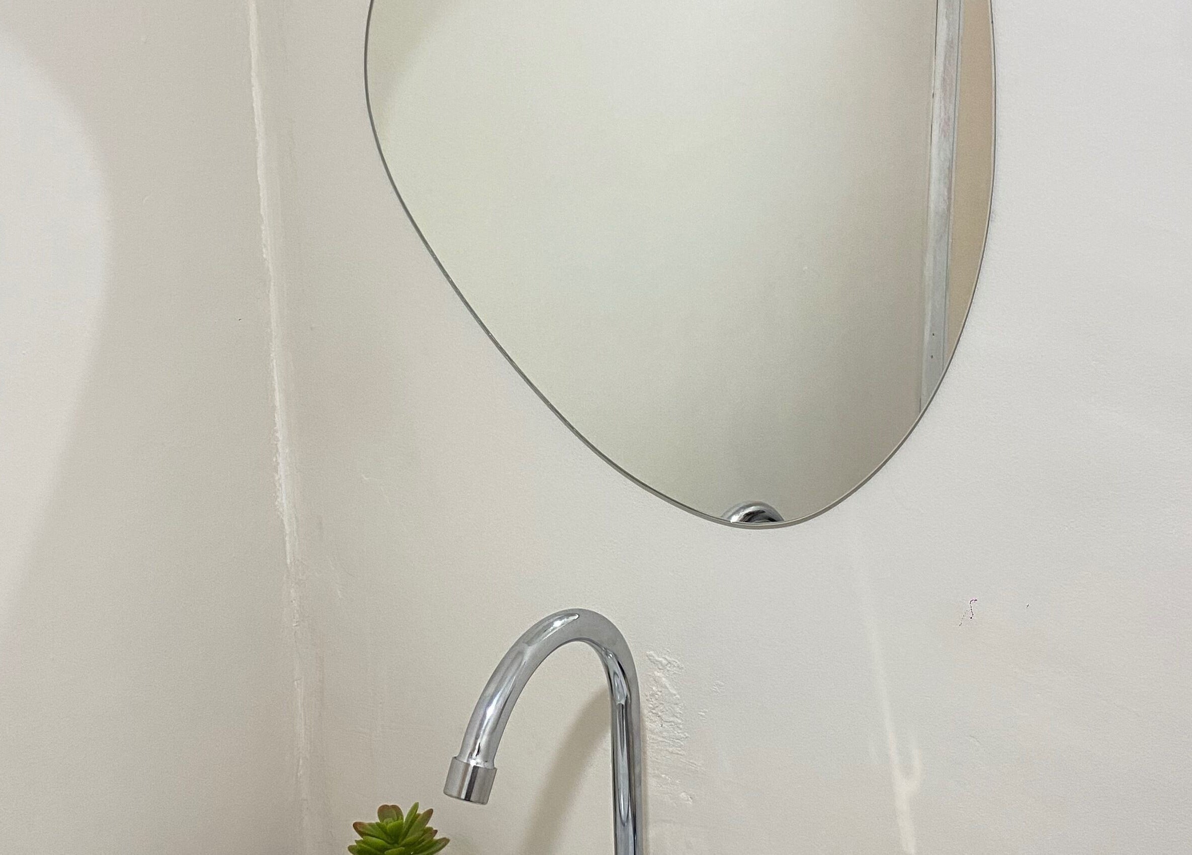 Espelho oval em Fran Souza Nails, São Paulo, SP. Decoraço elegante acima de pia moderna.