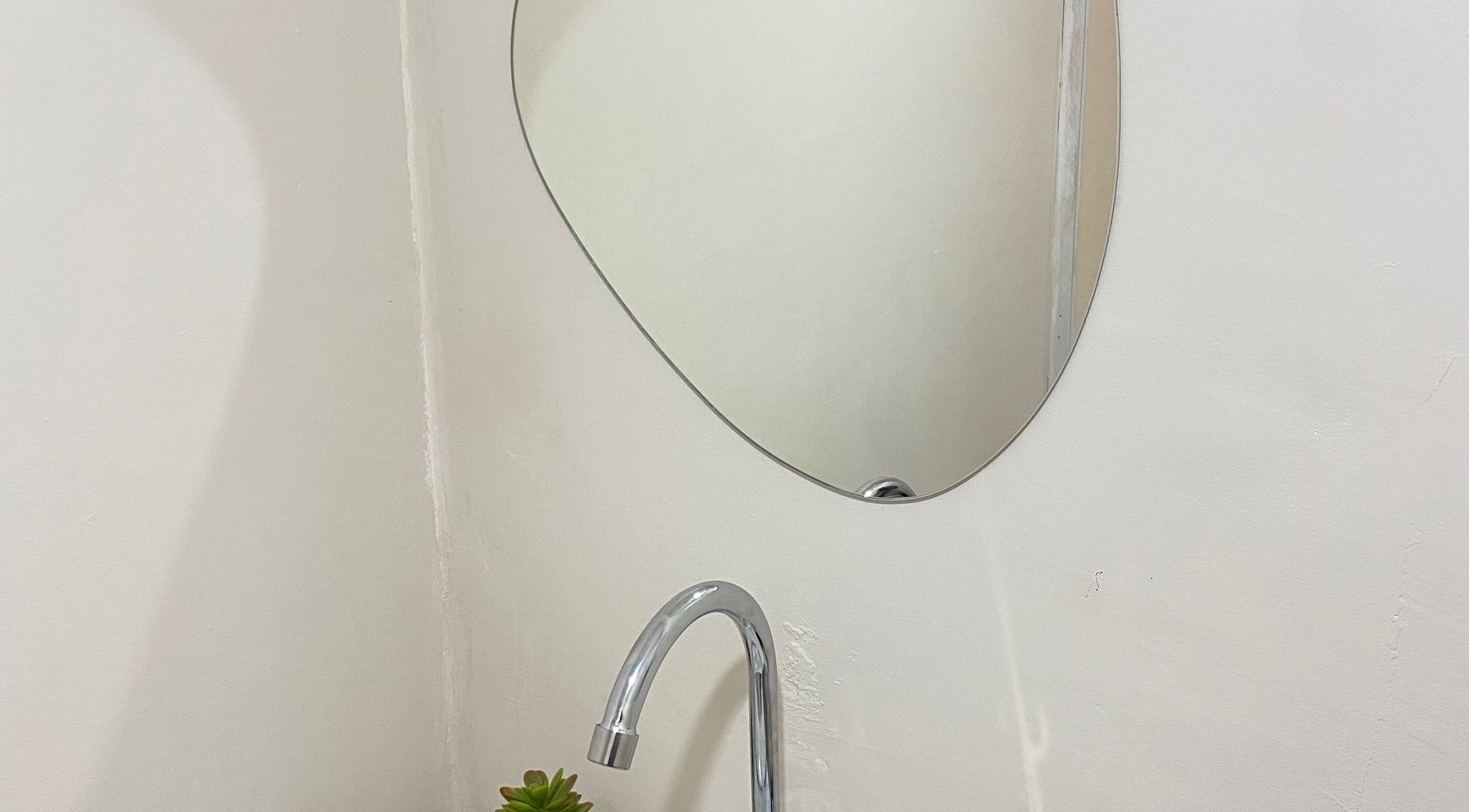 Espelho oval em Fran Souza Nails, São Paulo, SP. Decoraço elegante acima de pia moderna.