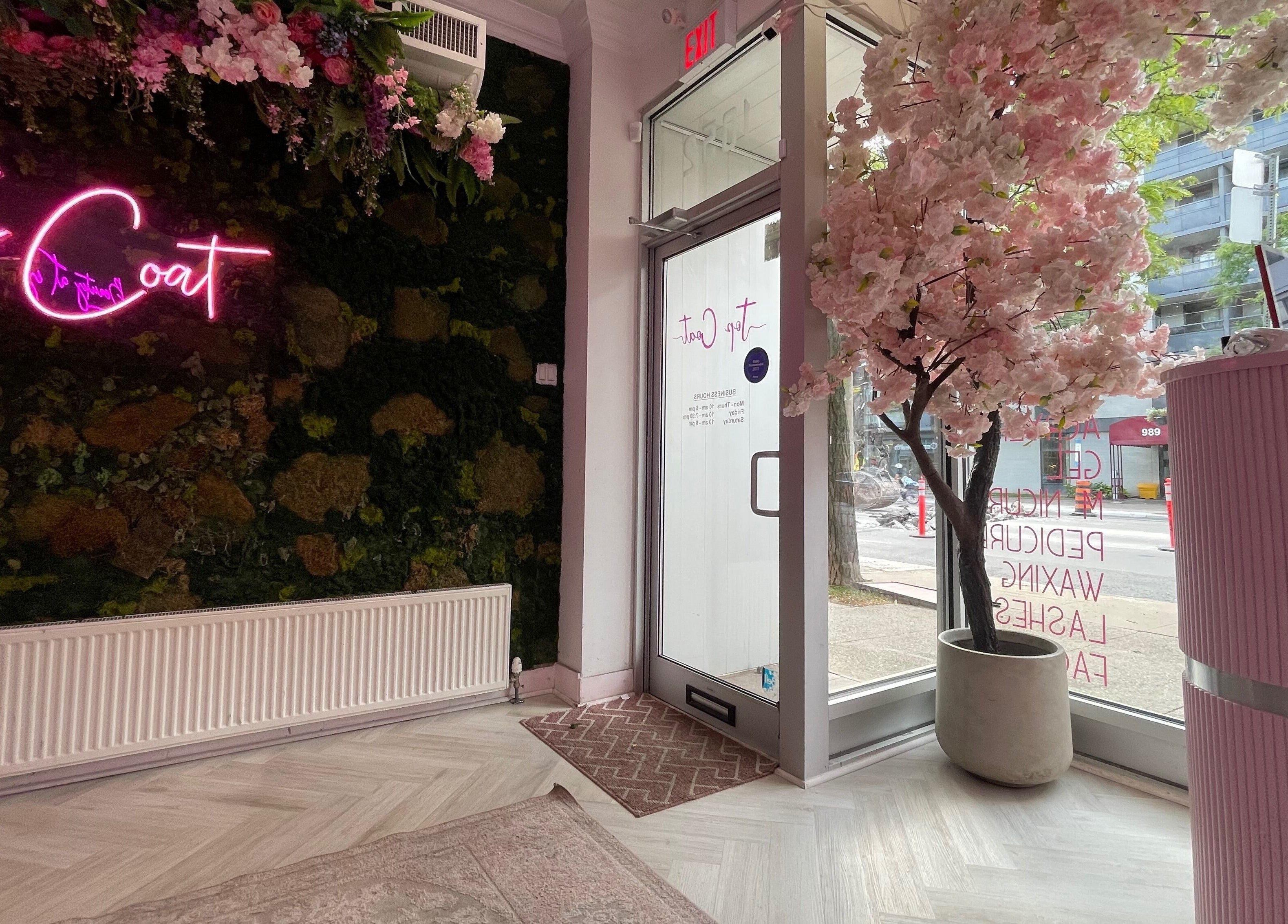 Inviting Top Coat entrance in Toronto, Ontario, CA, featuring neon sign and floral decor.
