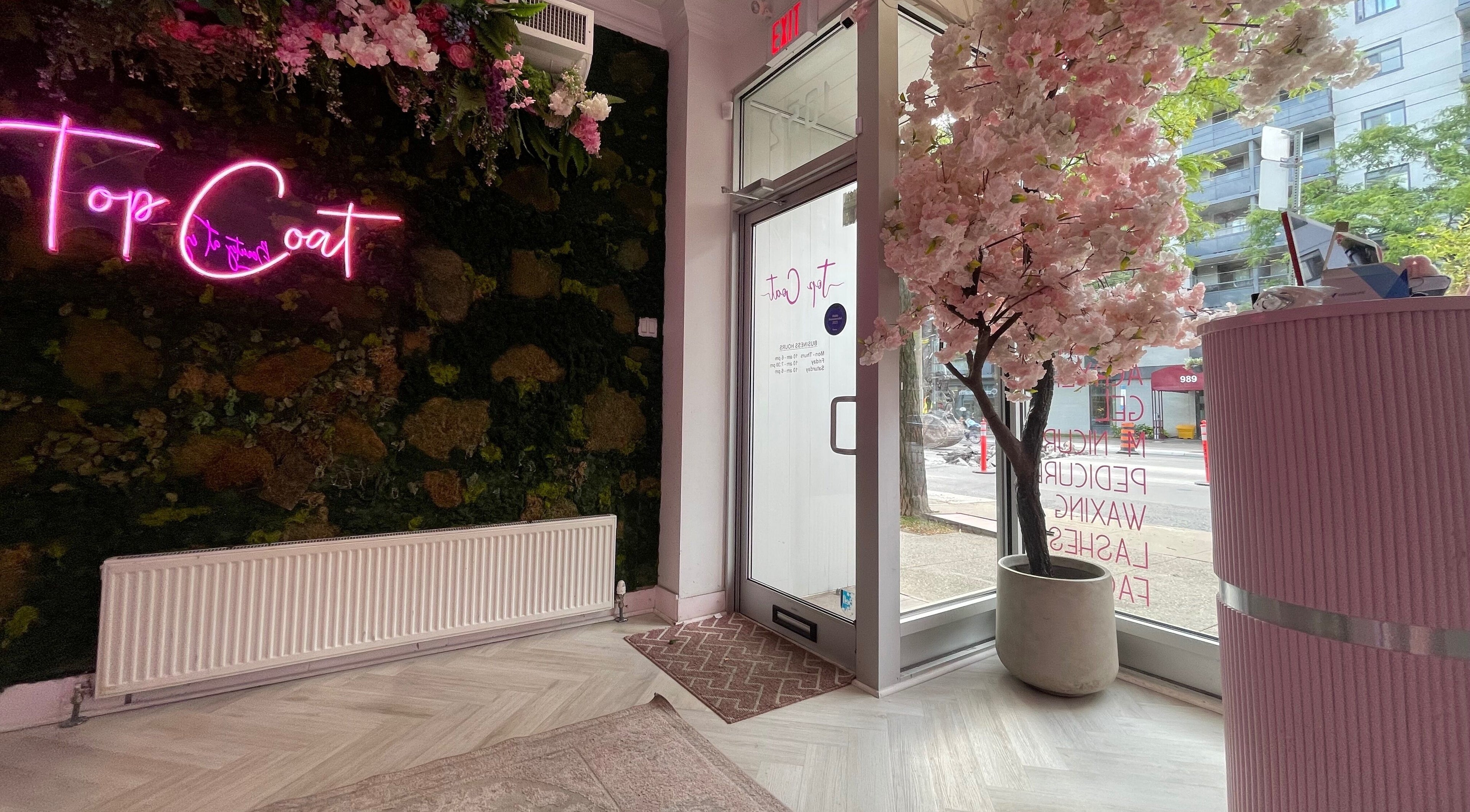 Inviting Top Coat entrance in Toronto, Ontario, CA, featuring neon sign and floral decor.
