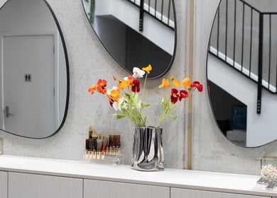 Elegant interior of Drader Brows in Auckland, NZ with vibrant flowers and modern mirrors.
