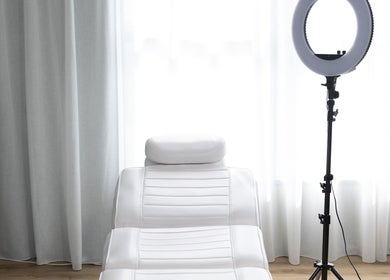 Elegant treatment room at Drader Brows in Auckland, Auckland, NZ, featuring a plush white spa bed and ring light.