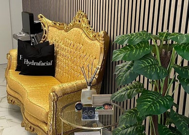 Elegant seating area at Laura O. Estética in Fuengirola, Andalucía, ES featuring a gold sofa and lush plant.
