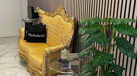 Elegant seating area at Laura O. Estética in Fuengirola, Andalucía, ES featuring a gold sofa and lush plant.