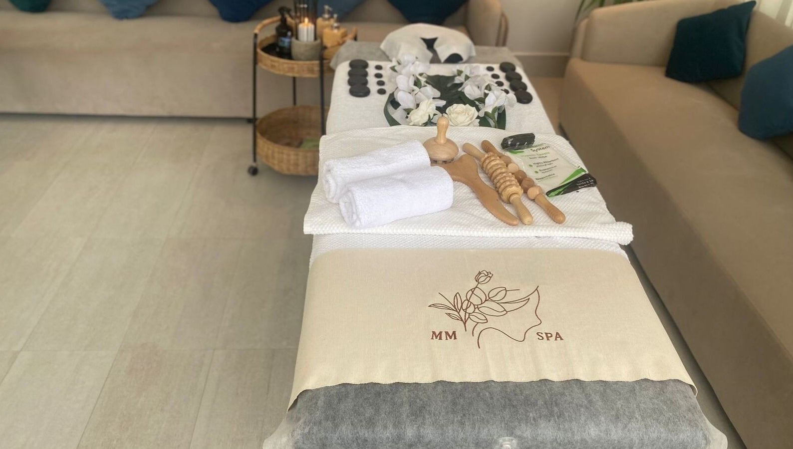 Luxurious spa setup at MMSPA - Home Service in Riyadh, SA, showcasing towels, wooden tools, and decor.