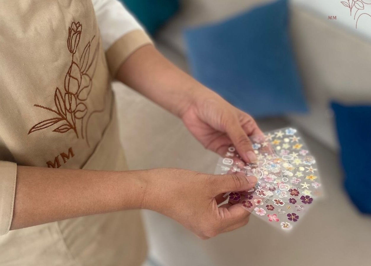 Person selecting nail art decorations at MMSPA - Home Service, Riyadh, SA for a personalized beauty experience.