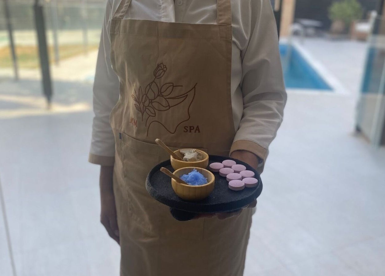 MMSPA - Home Service staff in Riyadh, SA offering a tray with wellness products by a poolside.