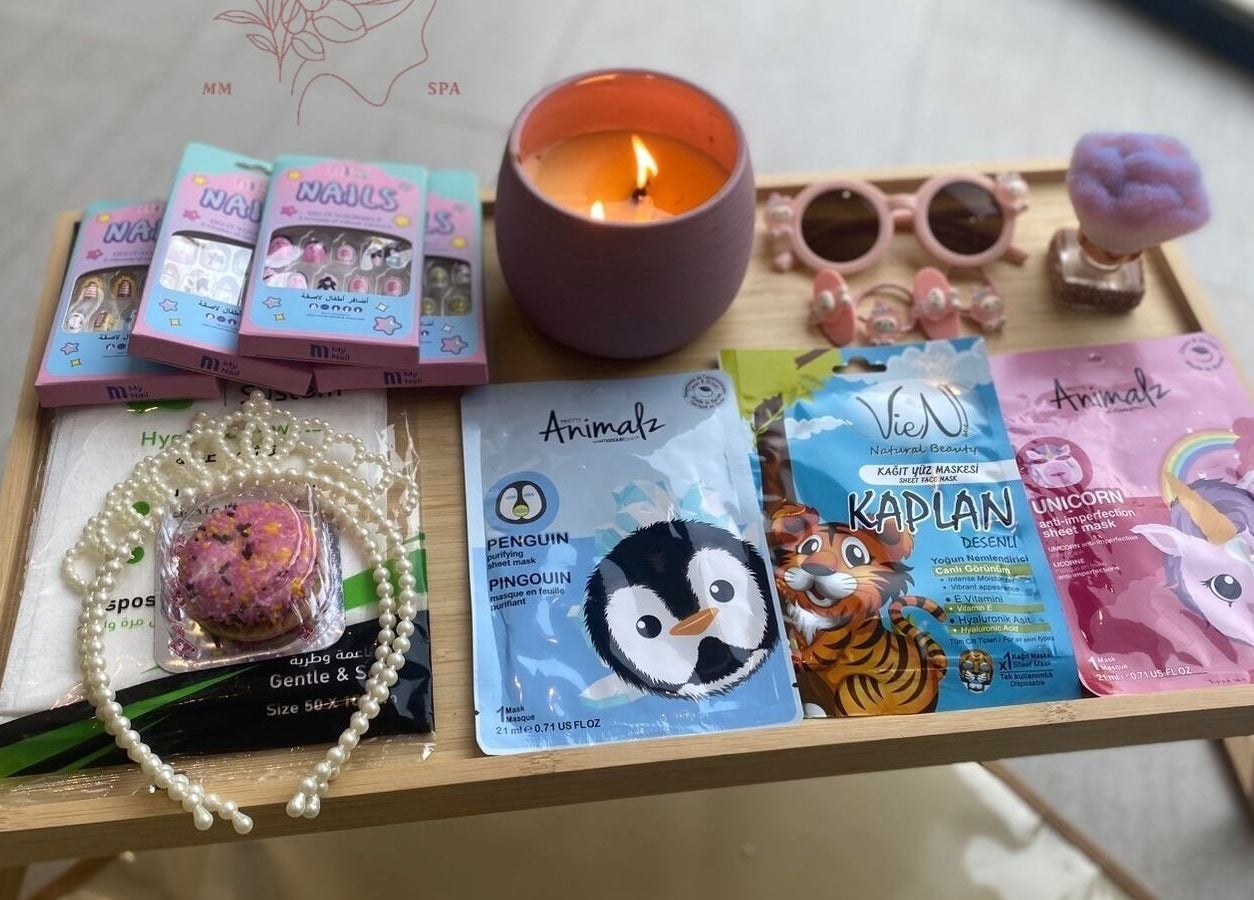 Beauty products at MMSPA - Home Service, Riyadh, SA including face masks, a candle, and accessories on a wooden table.