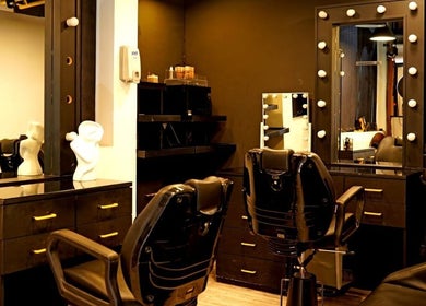 Modern styling stations at Sossi Beauty Center, Abu Dhabi, AE showcasing sleek black chairs and mirrors.