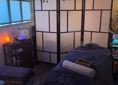 Calming spa room at Bow-tiful in Hoyland, England, GB, with ambient lighting and massage table.