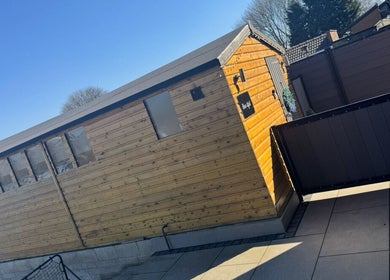 Exterior view of Bow-tiful, a wellness retreat in Hoyland, England, GB, with wooden siding under a clear sky.