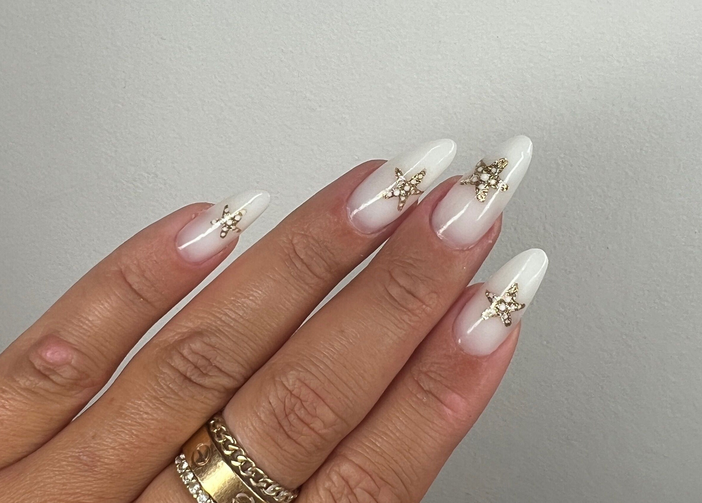 Elegant gold-embellished white nails at Aurora Beauty by Drea, San Pawl il-Baħar, MT.