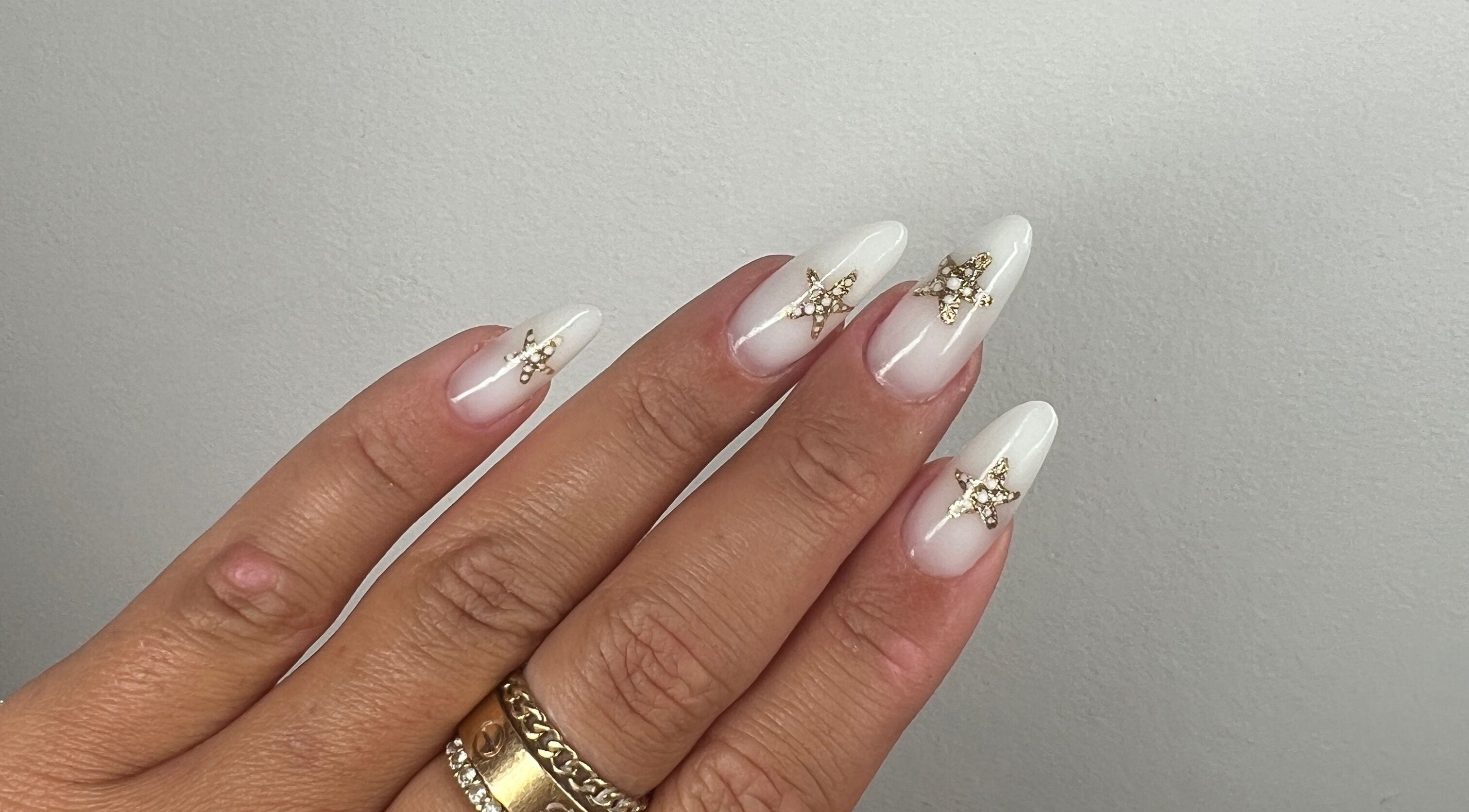 Elegant gold-embellished white nails at Aurora Beauty by Drea, San Pawl il-Baħar, MT.