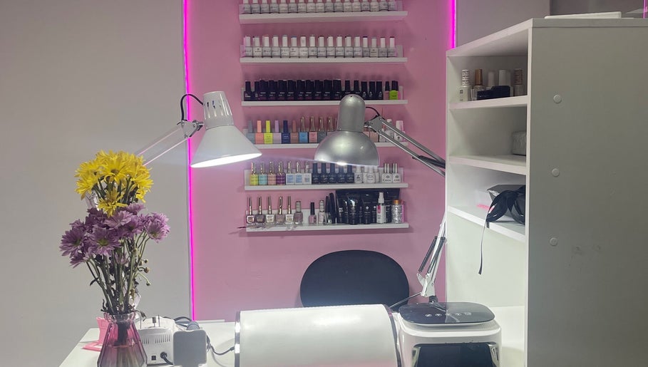 Mesa de manicura en Lili Glam Nails, Panamá City, con esmaltes y flores sobre fondo rosado.