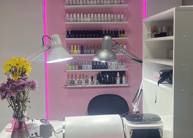 Mesa de manicura en Lili Glam Nails, Panamá City, con esmaltes y flores sobre fondo rosado.