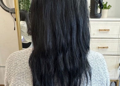 Mujer con cabello negro largo en salón Valcassi, Ensenada, Baja California, MX frente a espejo.