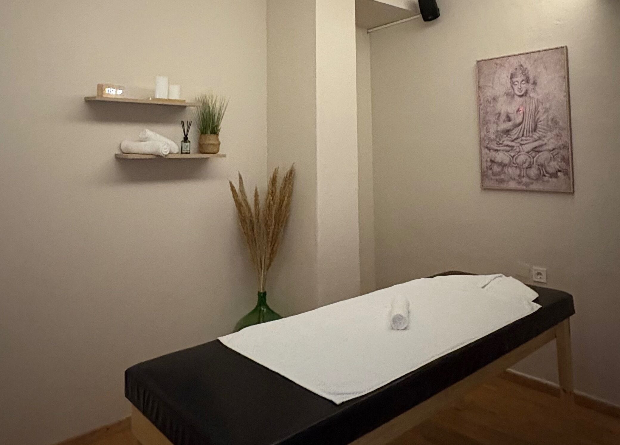 Δωμάτιο χαλάρωσης στο Serenity Massage Experience, Λάρισα, GR, με τραπέζι μασάζ και διακοσμητικά στοιχεία.