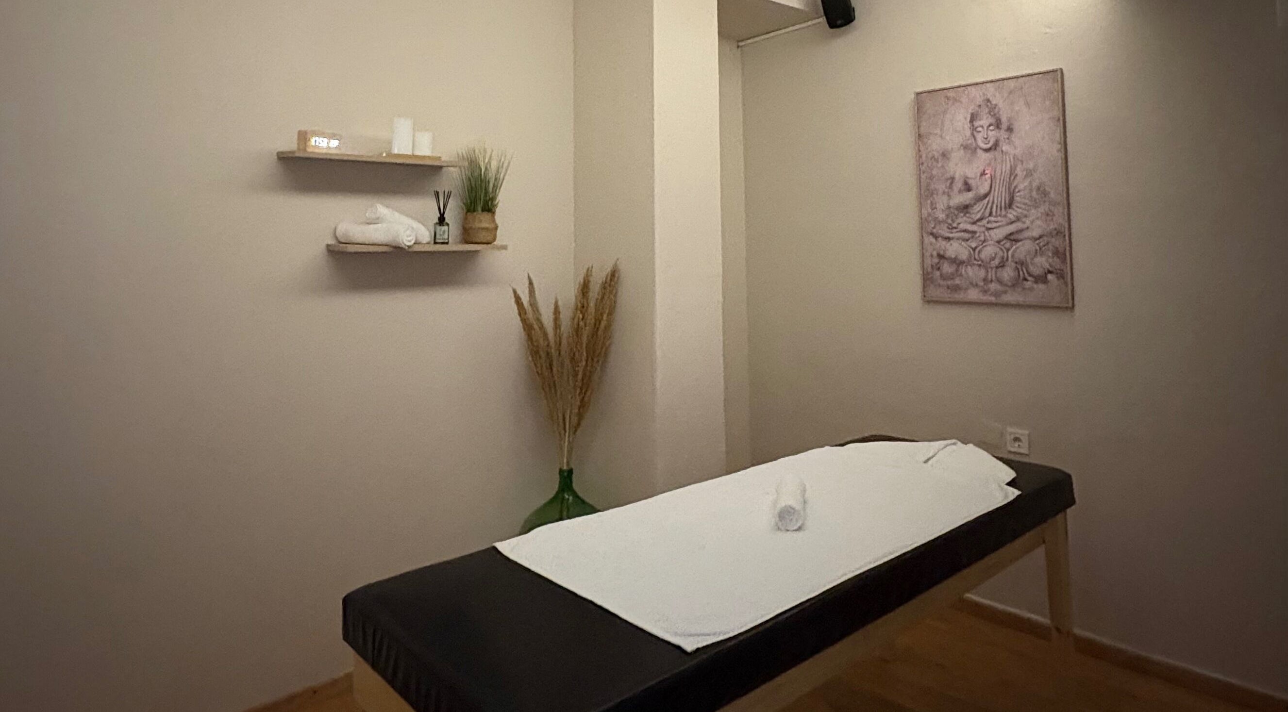 Δωμάτιο χαλάρωσης στο Serenity Massage Experience, Λάρισα, GR, με τραπέζι μασάζ και διακοσμητικά στοιχεία.