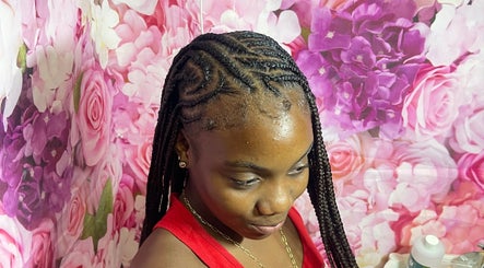 Intricate braids at Tressed By Jai, Roseau, Saint George Parish, DM, with a floral backdrop.
