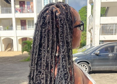 Dreadlocks styled at Tressed By Jai in Roseau, Saint George Parish, DM, with apartments in the background.