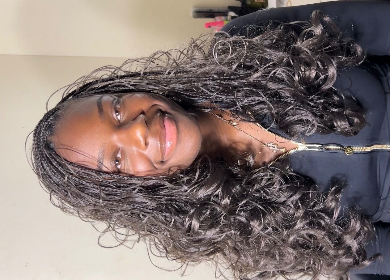 A smiling client with curly braids at Olutey in Toronto, Ontario, CA.