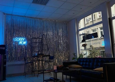 Stilvolle Lounge im Vean TATTOO Gotha, Thüringen, DE mit 'Sorry Mom' Neonlicht und gemütlichem Ambiente.