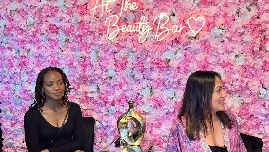 Women at LC Beauty Bar's floral wall in Apopka, Florida, US.