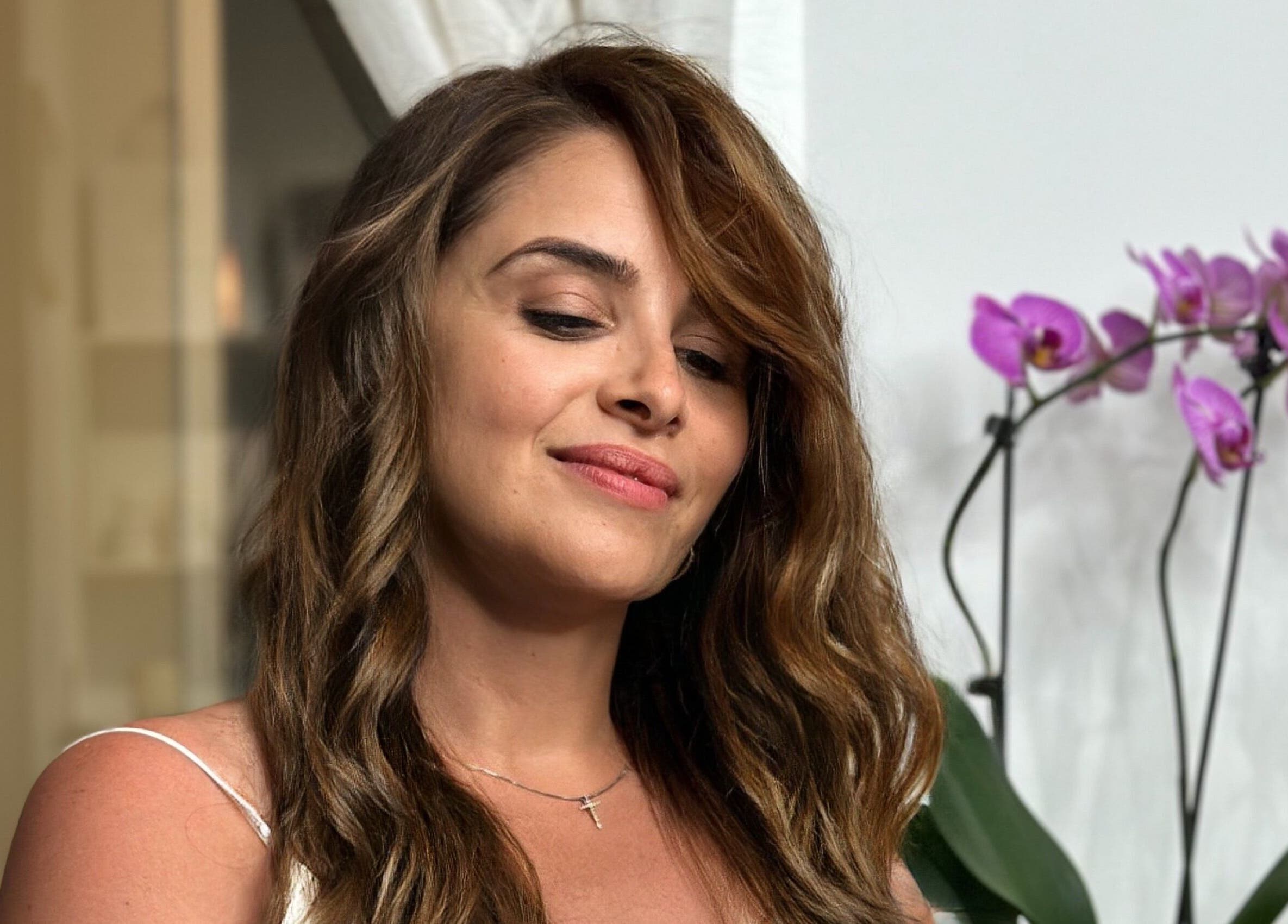 Woman with radiant curls at Lucas Hair Loft, Tampa, Florida, US, with orchids in the background.