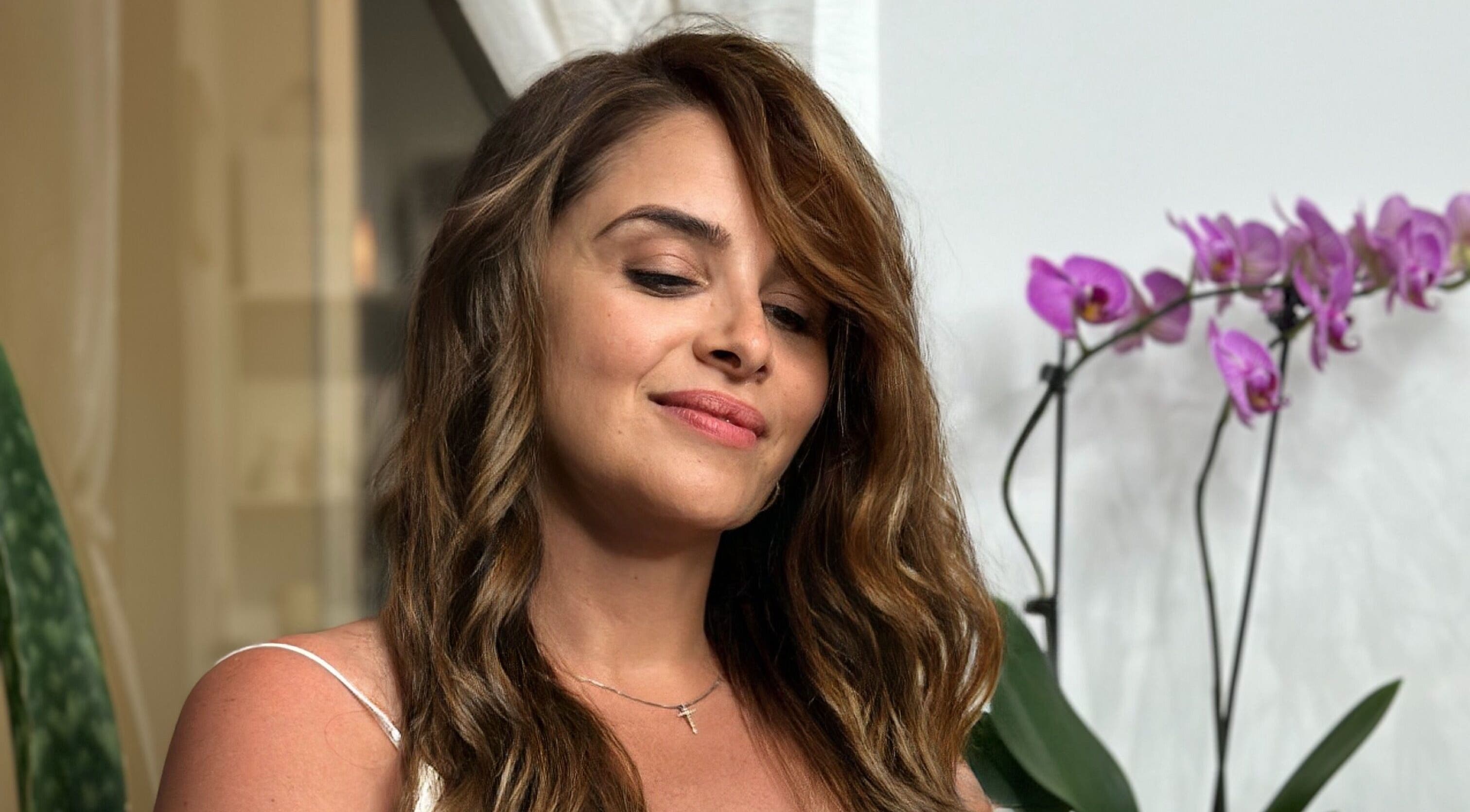 Woman with radiant curls at Lucas Hair Loft, Tampa, Florida, US, with orchids in the background.