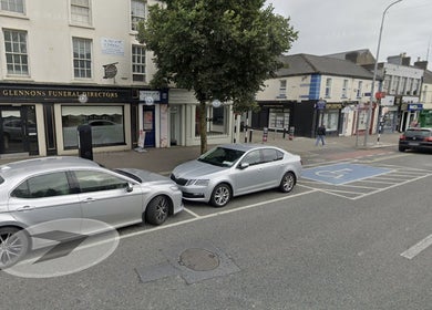 Downtown Newbridge near Eyelashes By Karolina with parked cars along a quiet street in County Kildare, IE.