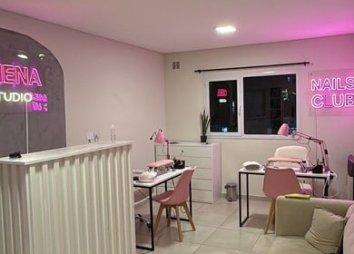 Interior moderno de Chena Studio, Cipolletti, Río Negro, AR con luces de neón rosa y estaciones de belleza.