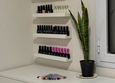 Variedad de esmaltes en estantería en Chena Studio, Cipolletti, Río Negro, AR con planta decorativa.
