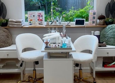 Aurora Beauty Studio in Newton Poppleford, England, GB showcases a modern nail station with white chairs and beauty products.