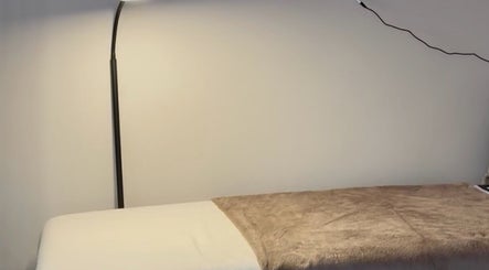 Cozy massage bed under soft lighting at Aurora Beauty Studio, Newton Poppleford, England, GB.