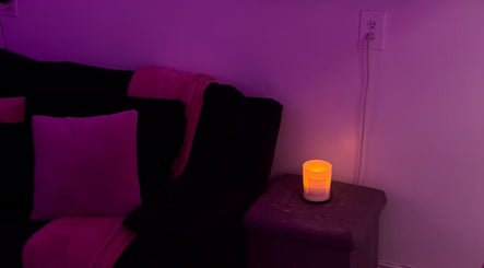 Cozy candlelit corner in The Nail Bar by Cortni, La Marque, Texas, US, featuring purple pillows and ambient lighting.