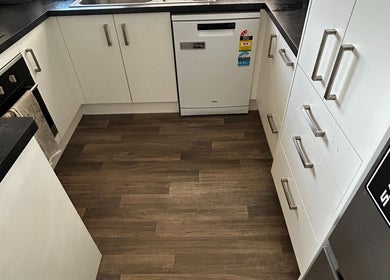 Modern kitchen at KJCleans, Manawatu, Manawatū-whanganui Region, NZ with white cabinetry and wood flooring.