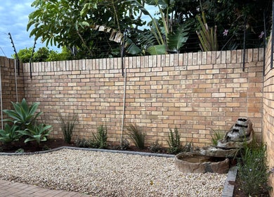Serene garden with brick wall and plants at Solare Studio, Gqeberha, Eastern Cape, ZA.