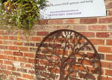 Decorative metal tree art and flowers on brick wall at Matter of Clarity, Finchampstead, England, GB.