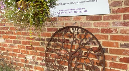 Decorative metal tree art and flowers on brick wall at Matter of Clarity, Finchampstead, England, GB.