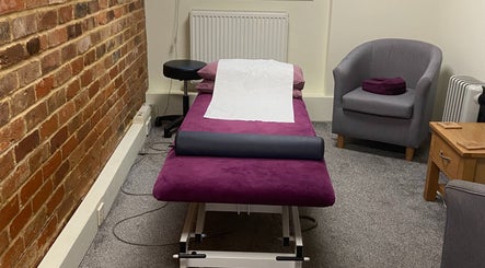 Cozy treatment room at Matter of Clarity, Finchampstead, England, GB with purple massage table and gray chair.